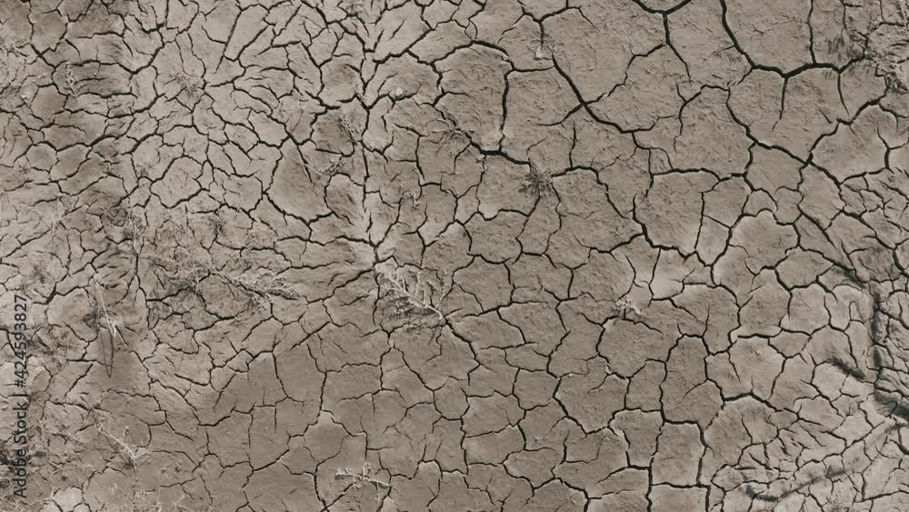 Dynamic shot of cracked soil ground of dried lake or river in mountains. Land destroyed by erosion and global warming - ecological issues concept Dynamic shot of cracked soil ground of dried lake or river in mountains. Land destroyed by erosion and global warming - ecological issues concept