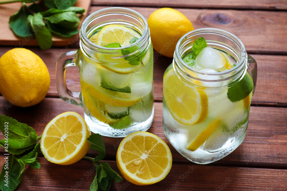 Fresh homemade citrus lemonade with lemons, mint and ice on a rustic wooden table. Summer cold refreshing drinks. Close-up, selective focus Fresh homemade citrus lemonade with lemons, mint and ice on a rustic wooden table. Summer cold refreshing drinks. Close-up, selective focus