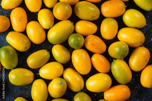 Top view. Pile of kumquats over blue background