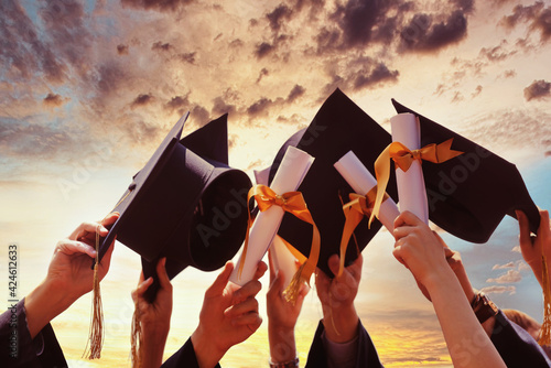 International students in mortar boards and bachelor gowns with diplomas.
