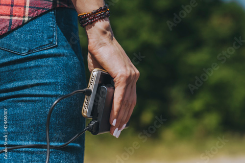 Close-up, Power Bank with a phone in the girl's hand. Against the backdrop of nature.