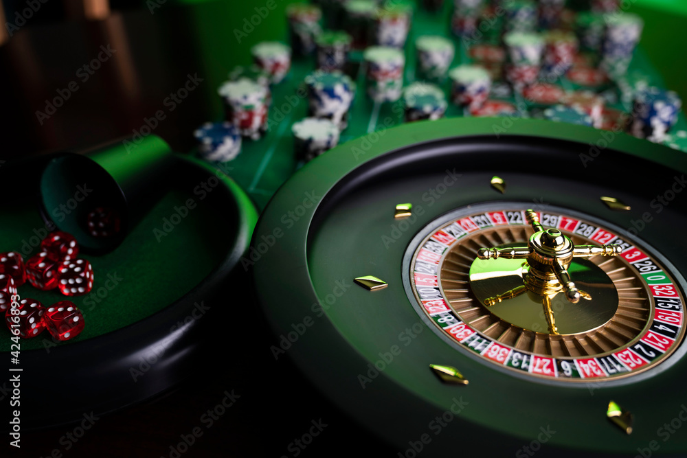 Casino. Gambling games theme. Roulette wheel, dice and poker chips on the casino felt green table. Casino. Gambling games theme. Roulette wheel, dice and poker chips on the casino felt green table.