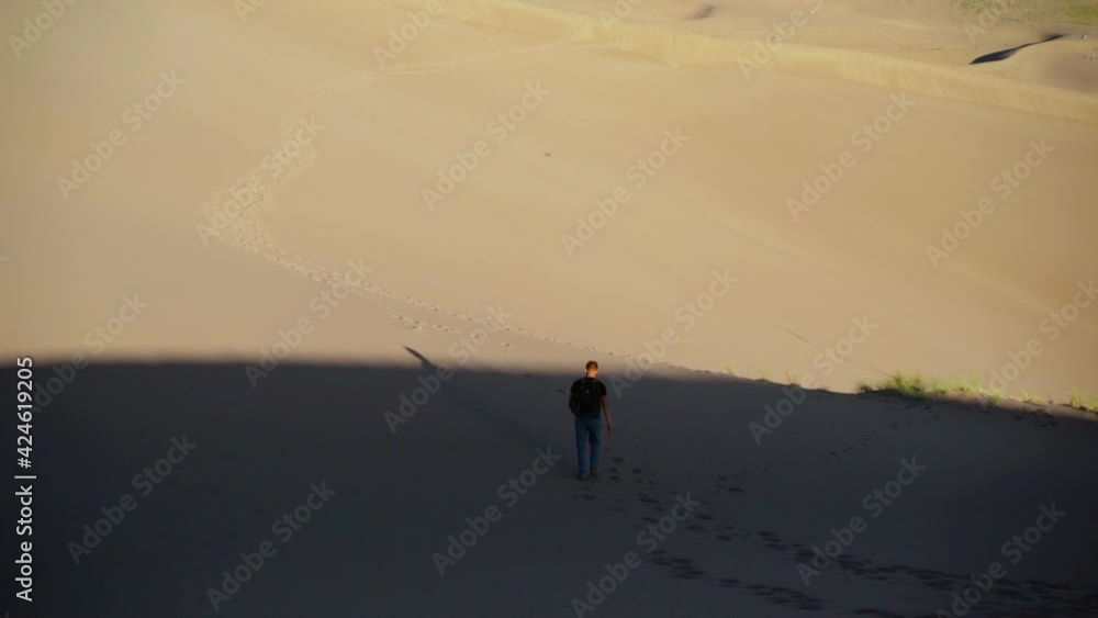 Man walking on dunes, sunny day, in Colorado, USA - static, slow motion shot Man walking on dunes, sunny day, in Colorado, USA - static, slow motion shot