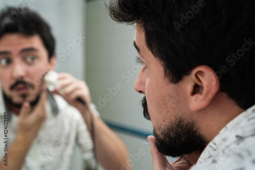 young man with beard trimming his beard with a beard trimmer