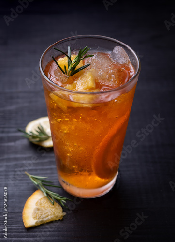 Orange iced tea in a glass on a rustic wooden background.