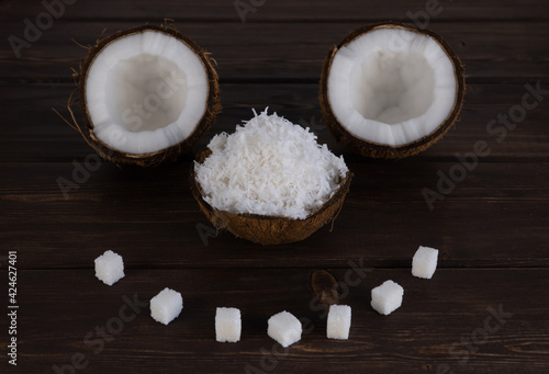 split coconut on wooden planks. selective focus. nut peel is filled with coconut shavings. Coco, ripe palm fruit. fruits are laid out in the form of a cheerful muzzle. faces made of food