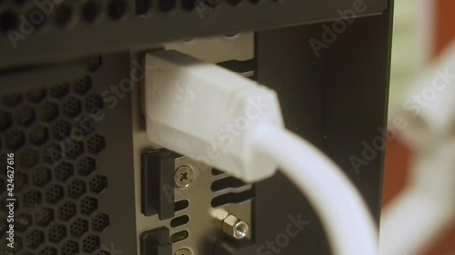 Close up shot showing the ports on a computer while a HDMI connector is plugged in, desktop compute and white cable. photo