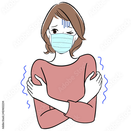 A woman wearing a facemask shivering from cold and feeling sick