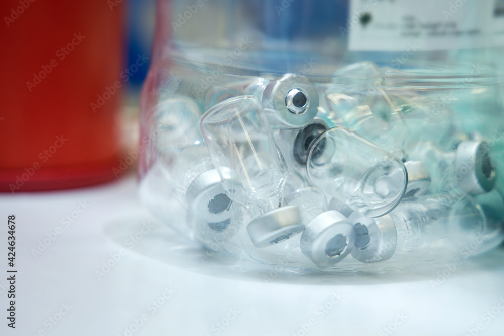 Empty hazard materials container for used vaccine bottles after vaccinate to person for corona virus (COVID-19) prevention. Piles of glass bottles for recycling. Empty hazard materials container for used vaccine bottles after vaccinate to person for corona virus (COVID-19) prevention. Piles of glass bottles for recycling.