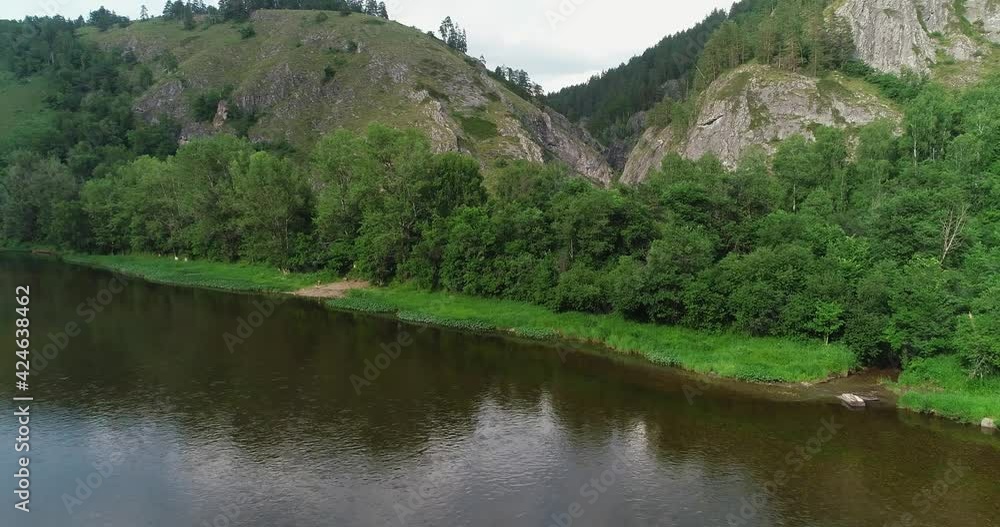 Kapova cave in Nature Reserve Shulgan-Tash. The entrance is huge arch with river flows out of ground. Limestone karst cave in the Burzyansky District of Bashkortostan. Aerial drone view at summer day Kapova cave in Nature Reserve Shulgan-Tash. The entrance is huge arch with river flows out of ground. Limestone karst cave in the Burzyansky District of Bashkortostan. Aerial drone view at summer day