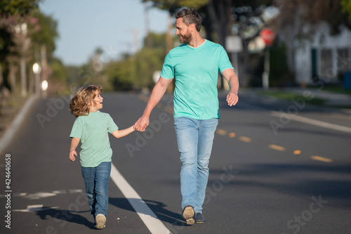 Father and son holding hands spending time outdoor together. Urban city walk family.