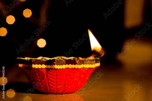 A Close up view of an earthen oil lamp lit against a bokeh background as a decoration of Deepavali festival of lights in India. photo