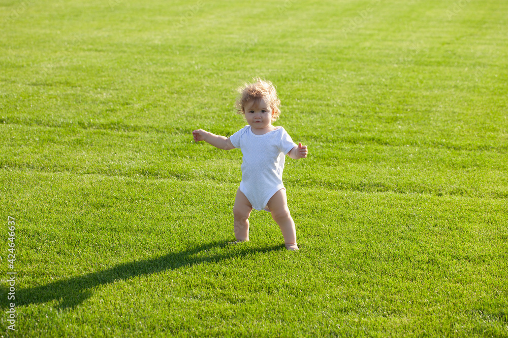 Baby standing barefoot on the green lawn. Healthy child. Baby standing barefoot on the green lawn. Healthy child.