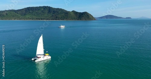 Aerial view. Catamaran goes by sea, camera move closer and fly over vessel, on the sunset, Beautiful view.