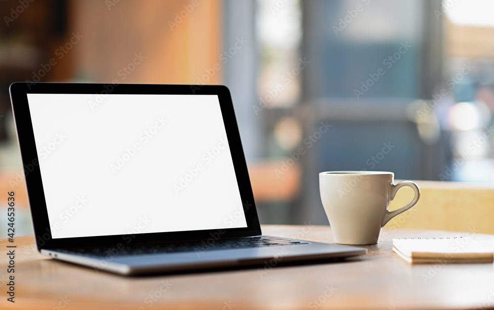 Mockup blank screen laptop with coffee and notebook on the table, Taken from the side. Mockup blank screen laptop with coffee and notebook on the table, Taken from the side.