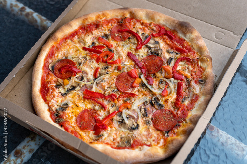 Pepperoni pizza in a box on a rusty table