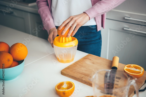 Caucasian woman is squeezing fresh citrus juice at home using a manual squeezer