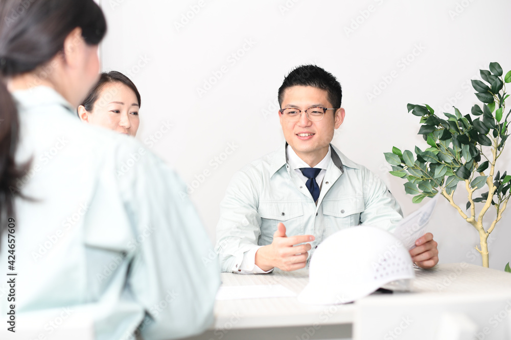 オフィスで会議をする作業服を着た男性と女性
