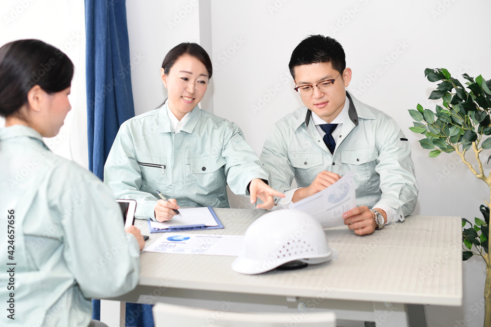 Fototapeta premium オフィスで会議をする作業服を着た男性と女性 