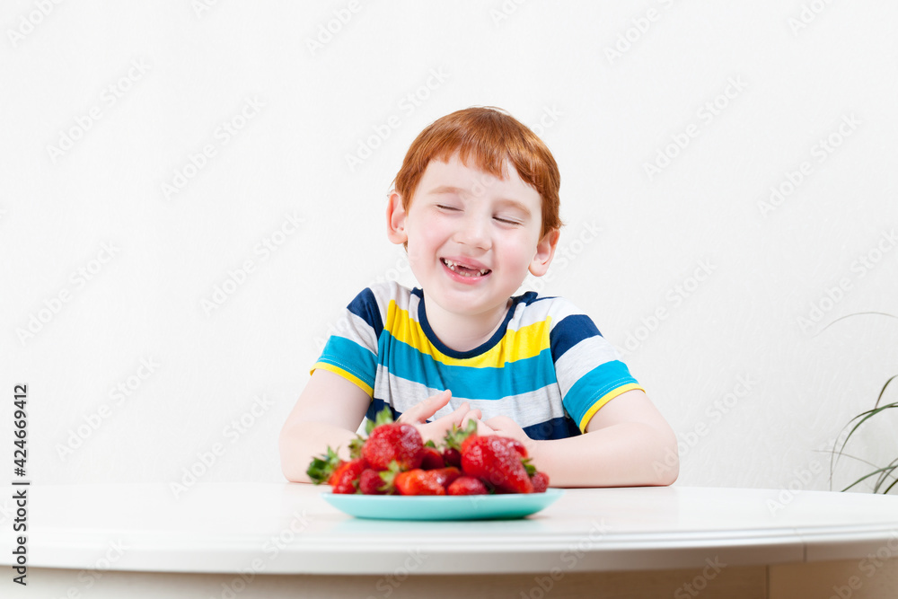 red-haired boy with ripe red strawberries, close-up portrait red-haired boy with ripe red strawberries, close-up portrait