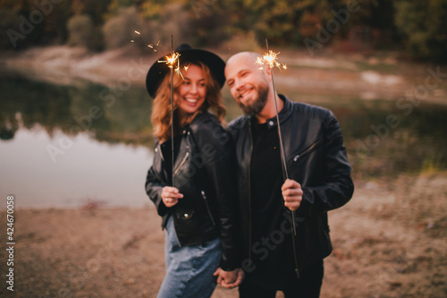 Happy couple in love standing with burning sparkles in an autumn forest.