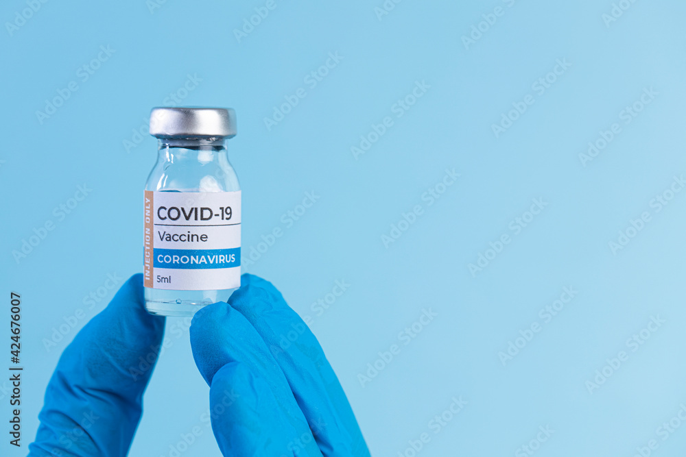 Hand in protective glove holds Covid-19 Vaccine glass vial. Hand in protective glove holds Covid-19 Vaccine glass vial.