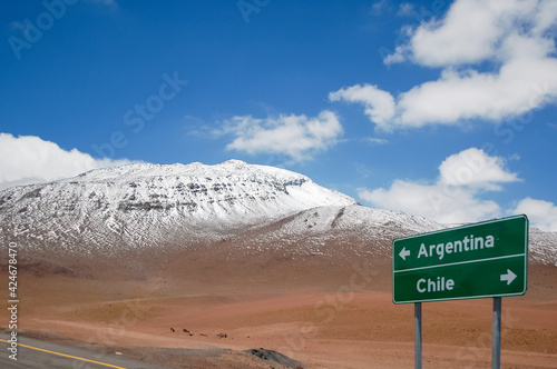 Highway sign with directions for Argentina and Chile at the border. Road sign in with mountain range and snow in the background. Road trip and adventure concept in South America. photo