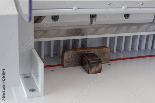 wooden pusher on automatic paper stack or label cutting machine, professional cutter, printing shop or workshop equipment.