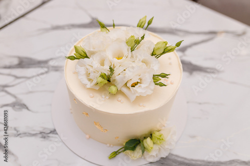 Soft focused close up shot of beautiful white wedding or birthday cake with roses flowers on marble background. Festive event sweet bakery