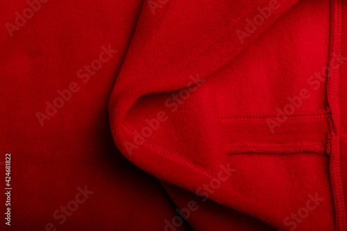 Texture of red fleece fabric and the inside or back side of it, background or backdrop. Clothing, sewing, gressmaking, haberdashery. Copy space.