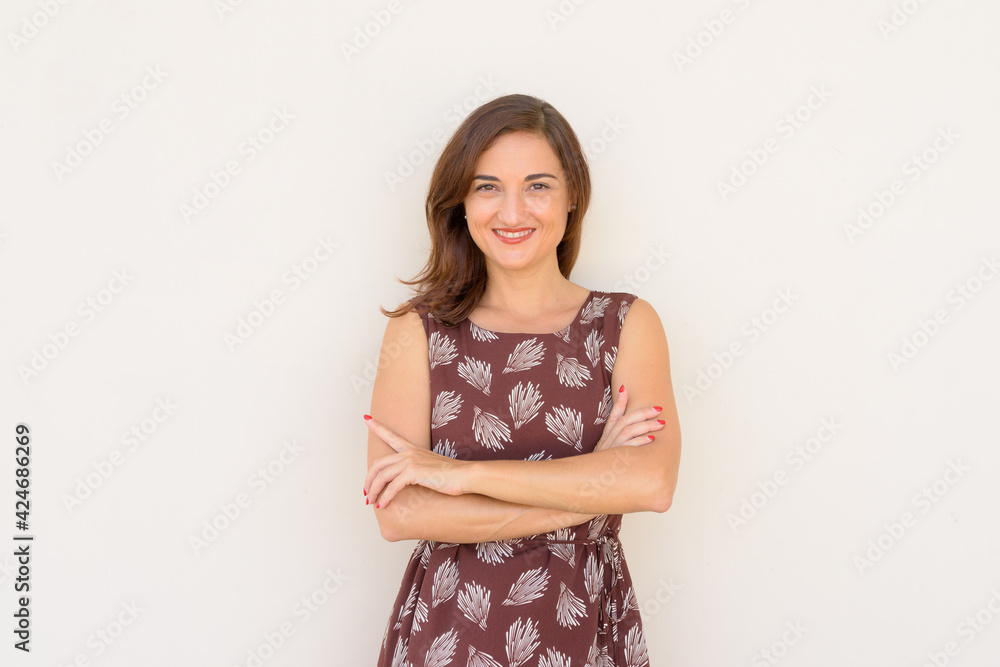 Portrait of beautiful woman smiling outdoors againt plain wall with arms crossed Portrait of beautiful woman smiling outdoors againt plain wall with arms crossed