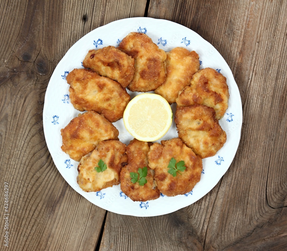 Pork schnitzels served on the plate. Decorated with sliced lemon and parsley. Brown rustic table. Top view, flat lay. Pork schnitzels served on the plate. Decorated with sliced lemon and parsley. Brown rustic table. Top view, flat lay.