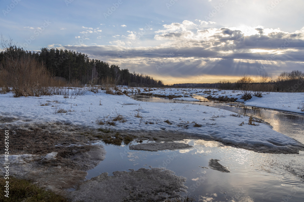 Sun through the clouds. Snow is melting. Early spring. Radiation of the river. Sun rays. Spring landscape Sun through the clouds. Snow is melting. Early spring. Radiation of the river. Sun rays. Spring landscape