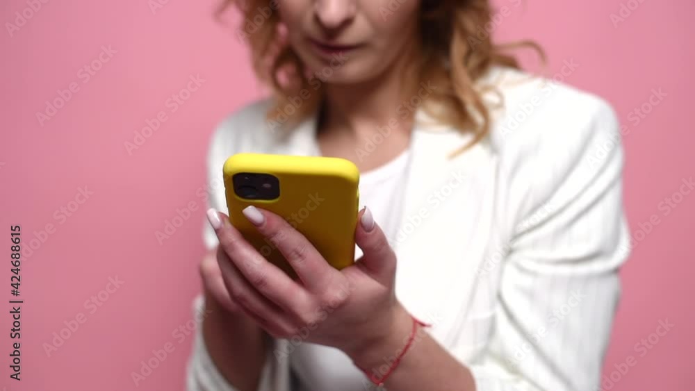 Texting swipe browsing social media for communication. Isolated on pink background in studio. A close-up shot of a woman climbing the phone Texting swipe browsing social media for communication. Isolated on pink background in studio. A close-up shot of a woman climbing the phone