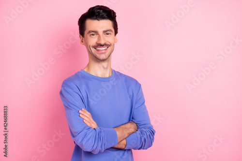Photo of brunet optimistic guy crossed arms wear blue shirt isolated on pink color background