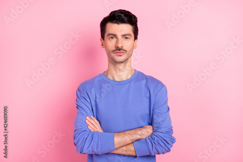 Photo of serious young charming man hold hands crossed confident wear blue sweater isolated on pink color background © deagreez