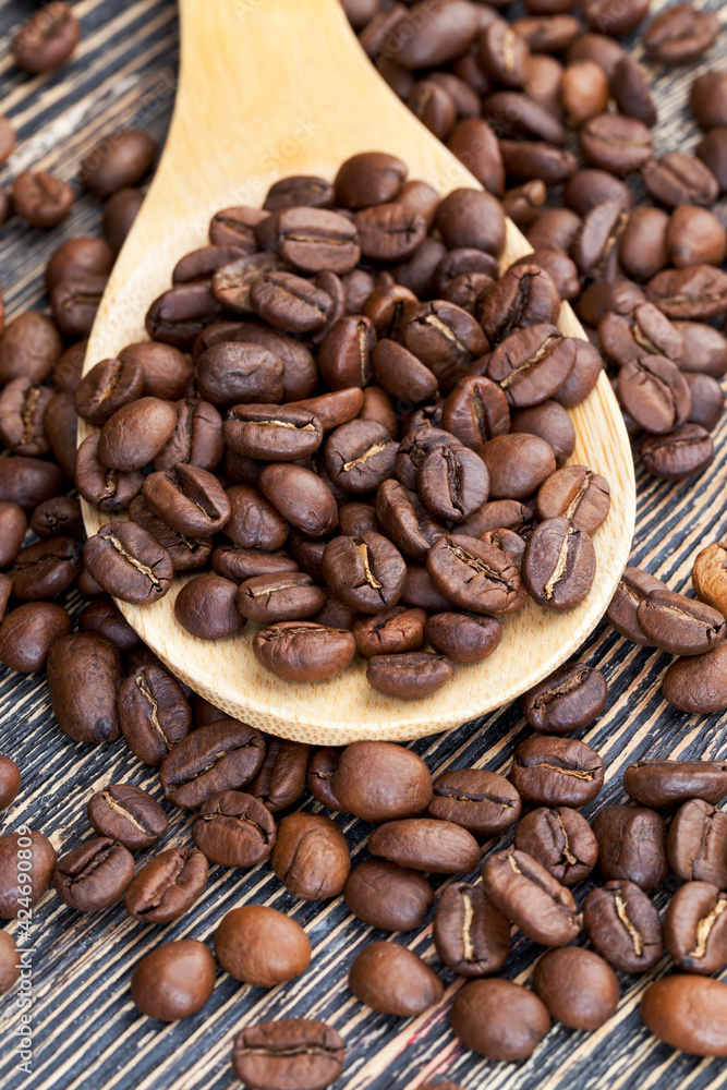 Fototapeta premium aromatic coffee beans in a wooden spoon