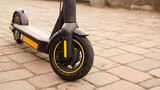 A close-up of the front wheel of an electric scooter against a tile backdrop.