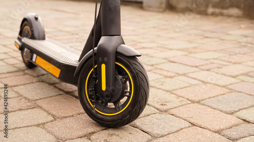 A close-up of the front wheel of an electric scooter against a tile backdrop. photo