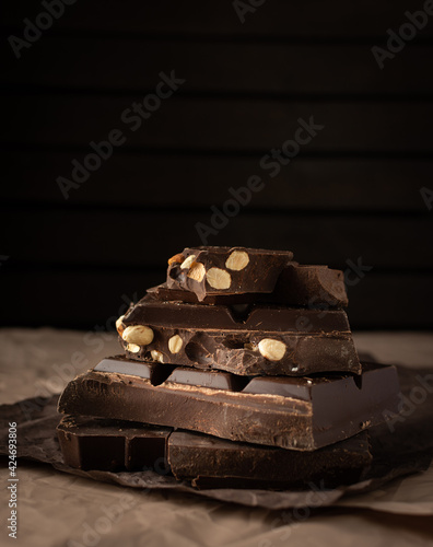 Dark chocolate with almonds and hazelnuts in a stack on brown background