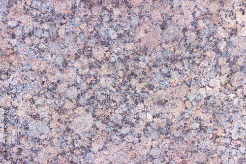 The texture of a hewn granite slab with a colorful pattern. Facing material for walls made of natural stone.