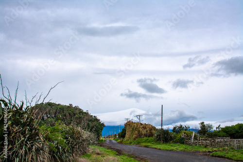 A country road heading towards Mount Taranaki under gray winter sky and dramatic clouds.