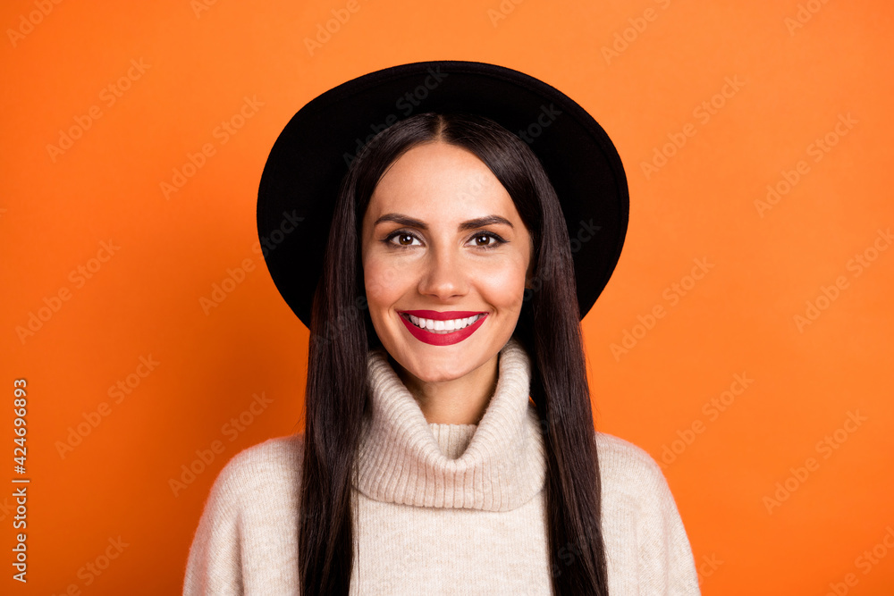 Photo of adorable sweet young lady dressed beige pullover cap smiling isolated orange color background Photo of adorable sweet young lady dressed beige pullover cap smiling isolated orange color background