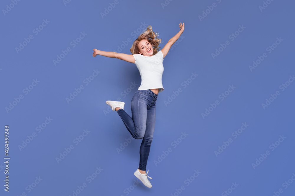 Full length body size view of attractive cheerful wavy-haired girl jumping having fun isolated over blue color background