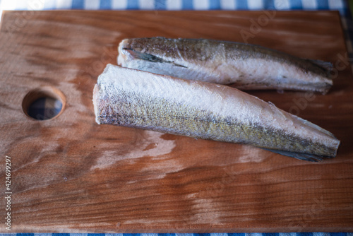 raw fish on a wooden board, healthy vegetarian food, frozen hake (Merluccius) on a kitchen board, fish cooking