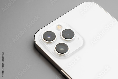 Close up of triple-lens camera of modern smartphone on gray background