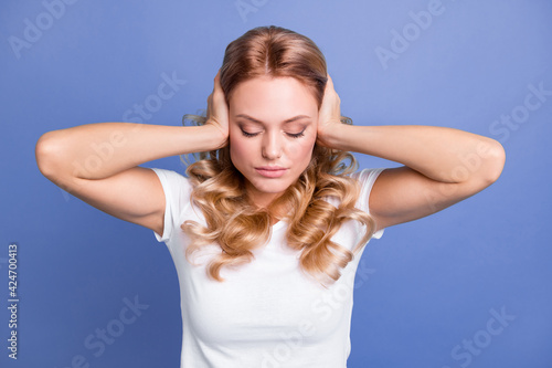 Photo of young unhappy upset suffering girl covering ears with hands avoid loud noises isolated on blue color background