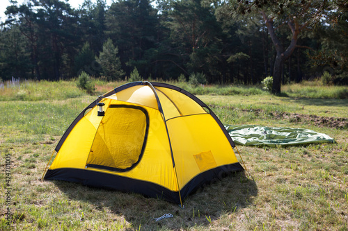 Installed tourist tent and a camping lantern in nature in the forest. Domestic tourism  active summer holidays  family adventures. Ecotourism  social distance. Copy space