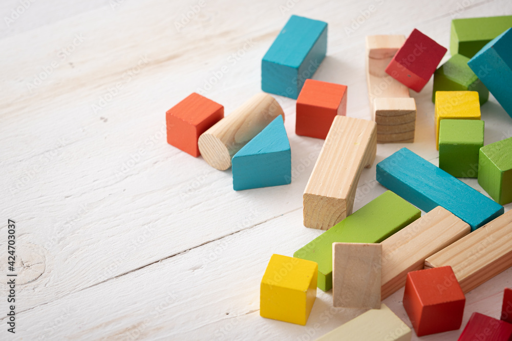 Obraz premium Closeup of colorful wooden toy blocks on white background wooden table. The child plays with colored cubes.