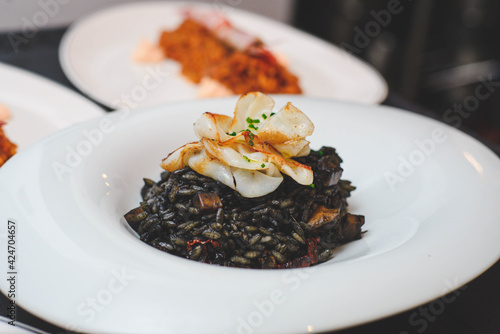 Un excelente plato gourmet de arroz negro de tinta de calamar estilo paella de marisco en un restaurante de lujo © dolores